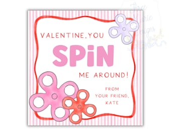 May include: A Valentine's Day card with a pink and red color scheme. The card features the words "VALENTINE, YOU SPIN ME AROUND!" in pink, along with three flower-shaped fidget spinners. The card is signed "FROM YOUR FRIEND, KATE."