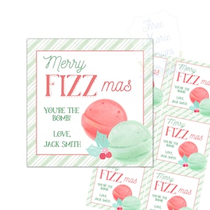May include: A square card with a green and white striped border and the words "Merry FIZZ mas" in red and green. Below the text are two bath bombs, one red and one green, with the text "YOU'RE THE BOMB!" and "LOVE, JACK SMITH."