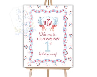 May include: Welcome to Ulysses' 1st birthday party sign with a red, white, and blue USA shield with stars and a blue ribbon border.