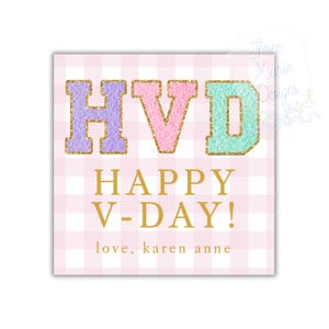 May include: A square card with a pink and white gingham pattern. The letters "HVD" are in pastel colors with gold glitter accents. Below, gold text reads "HAPPY V-DAY!" and "love, karen anne".