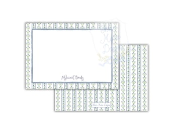 May include: Stationery set featuring a white notepad with a blue border and the name "Millicent Brady" in script. A matching card with a floral pattern in blue and green is also visible. The set is designed with a delicate, feminine aesthetic.