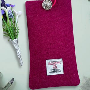 Pu&ograve; includere: Una custodia rettangolare in lana color magenta con una chiusura a bottone decorativo argentato e un passante elastico rosa. Un'etichetta bianca Harris Tweed &egrave; cucita sul davanti con la scritta Hand Woven Cloth Harris Tweed Outer Hebrides of Scotland 100% Pure New Wool.