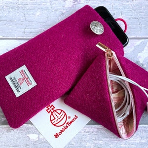 Pu&ograve; includere: Una custodia per telefono in Harris Tweed magenta con un bottone argentato e una pochette triangolare con cerniera abbinata contenente auricolari bianchi. Una carta bianca con il logo rosso Harris Tweed &egrave; posizionata sotto.
