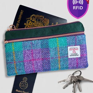 May include: A rectangular zippered pouch featuring a purple, teal, and yellow plaid Harris Tweed fabric with a dark green top panel. It includes a British passport, a set of metal keys, a Harris Tweed tag, and an RFID protection shield icon.