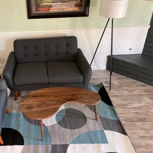 May include: A dark gray loveseat with a walnut wood kidney-shaped coffee table on a blue and white patterned rug.