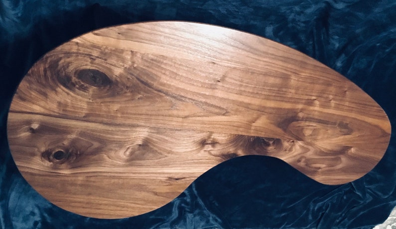 May include: A large, freeform, wooden serving tray made of walnut wood with a natural finish. The tray has a unique, organic shape and a smooth, polished surface.