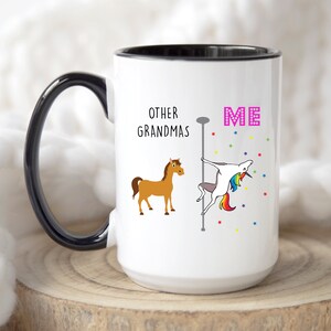 May include: White coffee mug with a black rim and handle. The mug has a graphic of a horse and a unicorn with the text "Other Grandmas" and "Me".