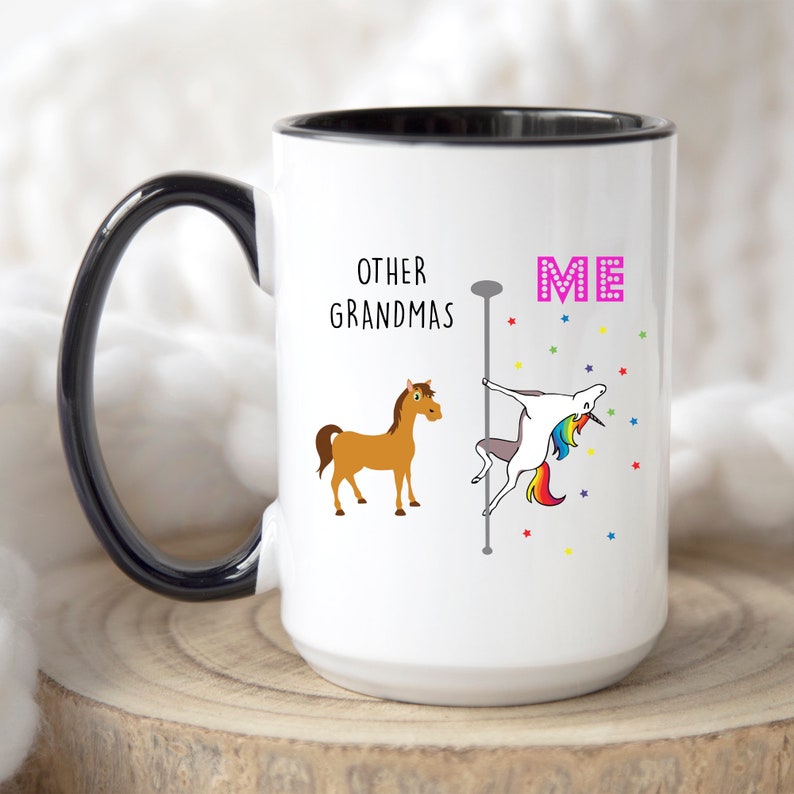 May include: White coffee mug with a black rim and handle. The mug has a graphic of a horse and a unicorn with the text "Other Grandmas" and "Me".