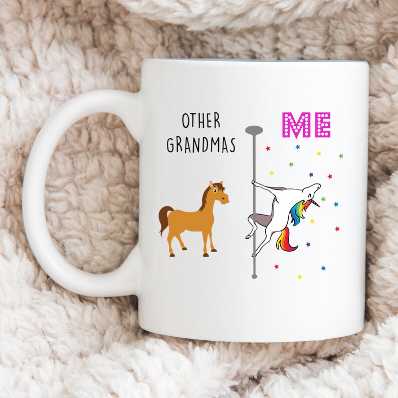 May include: White ceramic mug with a funny saying about grandmas. The text reads "Other Grandmas" with a picture of a brown horse and "Me" with a picture of a unicorn on a pole.