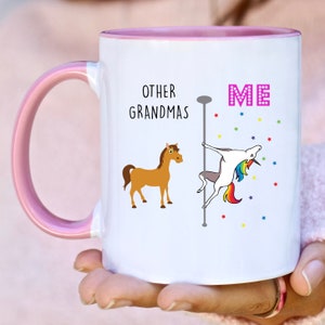 May include: White ceramic mug with a pink rim. The mug has a graphic of a horse and a unicorn with the text "Other Grandmas" and "Me".