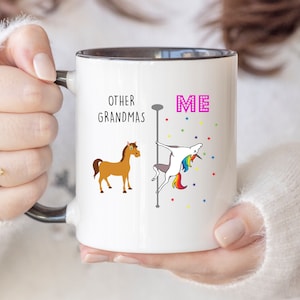 May include: White ceramic mug with a black rim. The mug has a brown horse and a unicorn on a pole with the text "Other Grandmas" and "Me" on the mug.