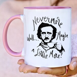 Puede incluir: Taza de caf&eacute; blanca con borde rosa. La taza presenta una ilustraci&oacute;n en blanco y negro de Edgar Allan Poe con el texto "Nevermore... well... a little more?"