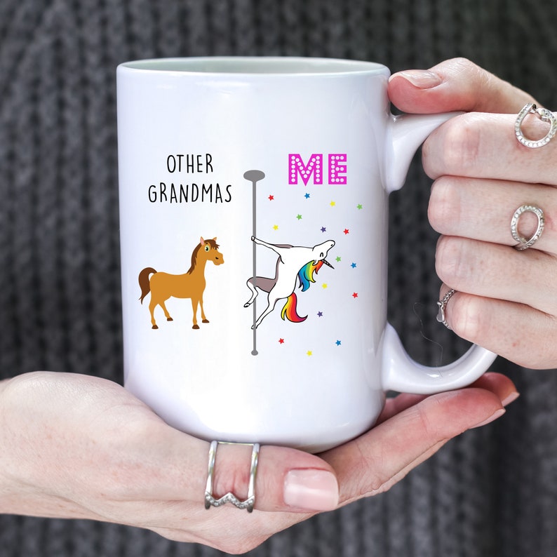May include: White ceramic coffee mug with a humorous design. The text reads "Other Grandmas" with a brown horse illustration. The text "ME" is in pink with a rainbow unicorn illustration on a pole.