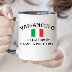 May include: White ceramic mug with a black rim and handle. The mug features a black and white graphic with the text "VAFFANCULO is ITALIAN for "HAVE A NICE DAY"" and an image of the Italian flag.