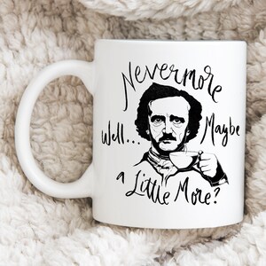Puede incluir: Taza de cer&aacute;mica blanca con una ilustraci&oacute;n en blanco y negro de Edgar Allan Poe sosteniendo una taza de caf&eacute;. La taza tiene el texto "Nevermore Well... a Little More?" impreso en ella.