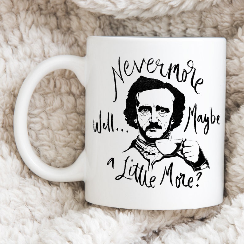 Puede incluir: Taza de cer&aacute;mica blanca con una ilustraci&oacute;n en blanco y negro de Edgar Allan Poe sosteniendo una taza de caf&eacute;. La taza tiene el texto "Nevermore Well... a Little More?" impreso en ella.