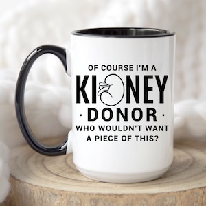 May include: White ceramic coffee mug with a black rim and handle. The mug has a black graphic that says "Of course I'm a Kidney Donor. Who wouldn't want a piece of this?"