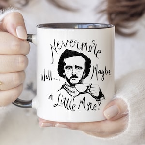 Puede incluir: Taza de cer&aacute;mica blanca con borde negro. La taza presenta una ilustraci&oacute;n en blanco y negro de Edgar Allan Poe con el texto "Nevermore well... a little more?"