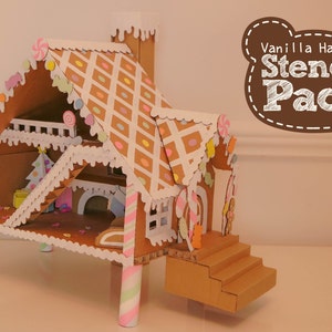 May include: A cardboard gingerbread house with a white and brown candy-themed exterior. The house has a white roof with a diamond pattern and a brown base. The house is decorated with candy canes, sprinkles, and other candy decorations. The house is on a white surface. The text "Vanilla Ham Ham Stencil Pack" is in a brown box with white text.