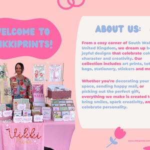 May include: A pink display table with various art prints, tote bags, and stationery. The text "WELCOME TO VIKKIPRINTS!" is displayed above the table. The display includes the text "SALE" and "ABOUT US:" with a description of the brand.