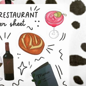 May include: A sticker sheet featuring a selection of restaurant-themed illustrations, including a loaf of bread, a glass of wine, a bottle of wine, a cocktail, and a menu. The sheet is white with black outlines and text that reads "The Restaurant Sticker Sheet".