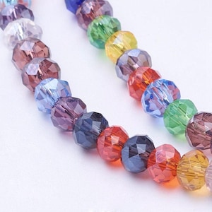 May include: A strand of colorful faceted glass beads. The beads are arranged in a rainbow pattern, with each bead a different color. The beads are strung on a clear thread.