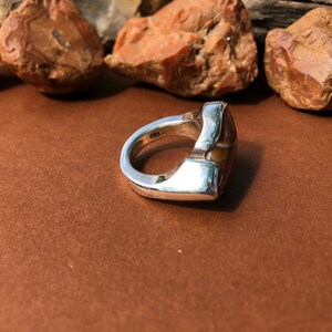 May include: A silver ring with a brown and white agate stone set in a geometric design.