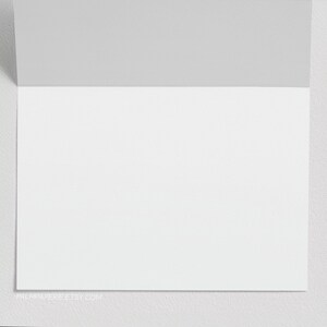 May include: A blank white card with a gray border. The card is folded in half and has a website address printed on the bottom.