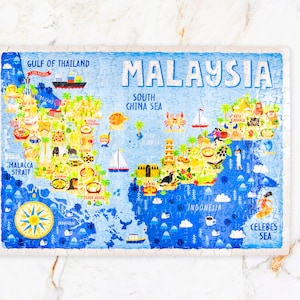 Pode incluir: Um quebra-cabeça colorido que representa um mapa da Malásia com vários marcos e ilustrações. O quebra-cabeça está sobre uma superfície branca com um lápis e selos.