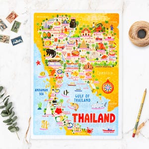May include: A colorful illustrated map of Thailand with the text "THAILAND" in red letters. The map shows various landmarks and icons, including temples, elephants, and boats. The map is on a white background with a blue border.
