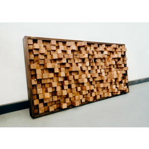 May include: A large wooden sound panel made of many small, square blocks. The panel is brown and has a natural wood finish. It is mounted on a wall and is a great way to improve the acoustics of a room.
