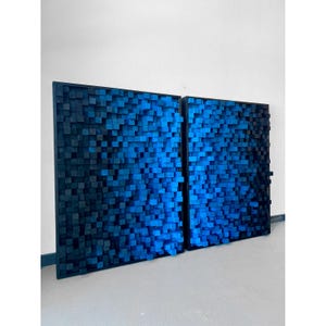 May include: Two black framed wall art pieces made of blue wooden blocks. The blocks are arranged in a gradient pattern, starting with dark blue and transitioning to light blue.