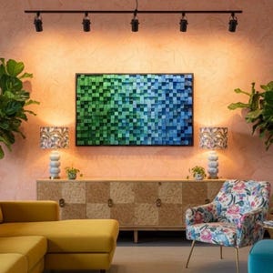 May include: A rectangular wall art piece composed of small, square wooden blocks arranged in a gradient from green to blue. The artwork is mounted on a textured peach-colored wall above a wooden sideboard, flanked by two lamps and two large potted plants.