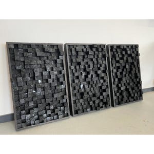 May include: Three black sound-absorbing panels made of wood blocks. Each panel is rectangular and has a unique pattern of wood blocks.