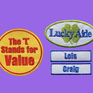 Puede incluir: Parches bordados con texto y diseños. Un parche circular amarillo con texto rojo que dice "The 'T' Stands for Value". Un parche ovalado con un trébol verde y las palabras "Lucky Aide". Dos parches con nombres.