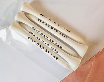 May include: Four white golf tees with the text "BEST DAD BY PAR" printed in black. The tees are packaged in a clear plastic sleeve. A perfect gift for any golf-loving dad.