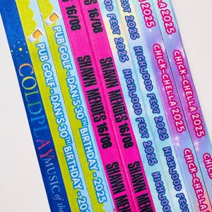 May include: A collection of colorful event wristbands with text. The bands feature phrases like "Shawn Mendes 16/08", "Highwood Fest 2025", and "Chick-Chella 2025". Other bands say "Pub Golf-Dan's 30th Birthday-2025" and "Coldplay Music of the Sphere".