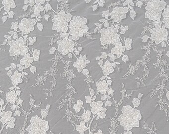 May include: White floral lace fabric with a delicate beaded design. The lace features a repeating pattern of small flowers and leaves.