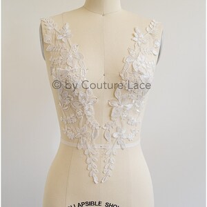 Könnte beinhalten: Weiße Spitzenapplikation mit floralen Designs, perfekt um einem Brautkleid oder einem anderen Kleidungsstück einen Hauch von Eleganz zu verleihen. Die Applikation ist auf einer Schaufensterpuppe zu sehen.