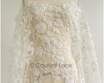 May include: White floral lace fabric with a delicate pattern of flowers and leaves. The lace is shown draped over a dress form.