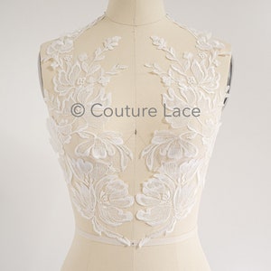 May include: White floral lace applique with delicate floral designs. The lace is on a white mannequin and the text "Couture Lace" is visible in the center of the image.