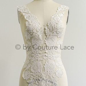 May include: White lace applique with floral designs, perfect for adding a touch of elegance to a wedding dress or other garment. The lace is delicate and intricate, with a variety of floral motifs. The applique is shown on a dress form, and the text "FOR INSPIRATION USED 2X A22-313" and "© by Couture Lace" are visible.