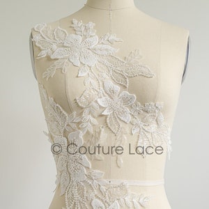 May include: White floral lace applique with beaded details. The lace is shown on a dress form with the words "COLLAR" and "SHOULDER" marked on the form.