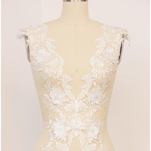 May include: White lace applique with a floral design. The lace is shown on a dress form with the text "COLLAPSIBLE SHOULDER" and the number "6" visible.