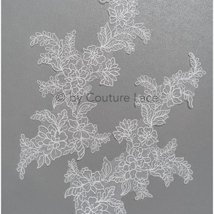 Op de afbeelding: Witte kant applique met een bloemenmotief. De kant is delicaat en ingewikkeld, met kleine bloemen en bladeren. De applique is perfect om een ​​toets van elegantie aan elk project toe te voegen.