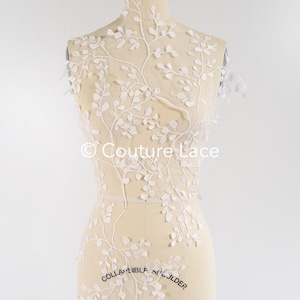 May include: White floral lace applique with delicate branches and leaves. The lace is displayed on a dress form. The text "Couture Lace" is visible on the lace.