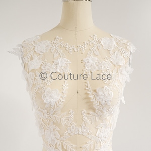 Può includere: Applique in pizzo bianco floreale con perline. Il pizzo è delicato e intricato, con una varietà di forme e dimensioni di fiori. L'applique è perfetta per aggiungere un tocco di eleganza a qualsiasi capo.