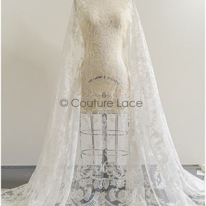 May include: White lace fabric with a delicate floral pattern. The lace is shown draped over a dress form. The fabric is sheer and has a soft, flowing texture. The text "Couture Lace" is visible on the fabric.