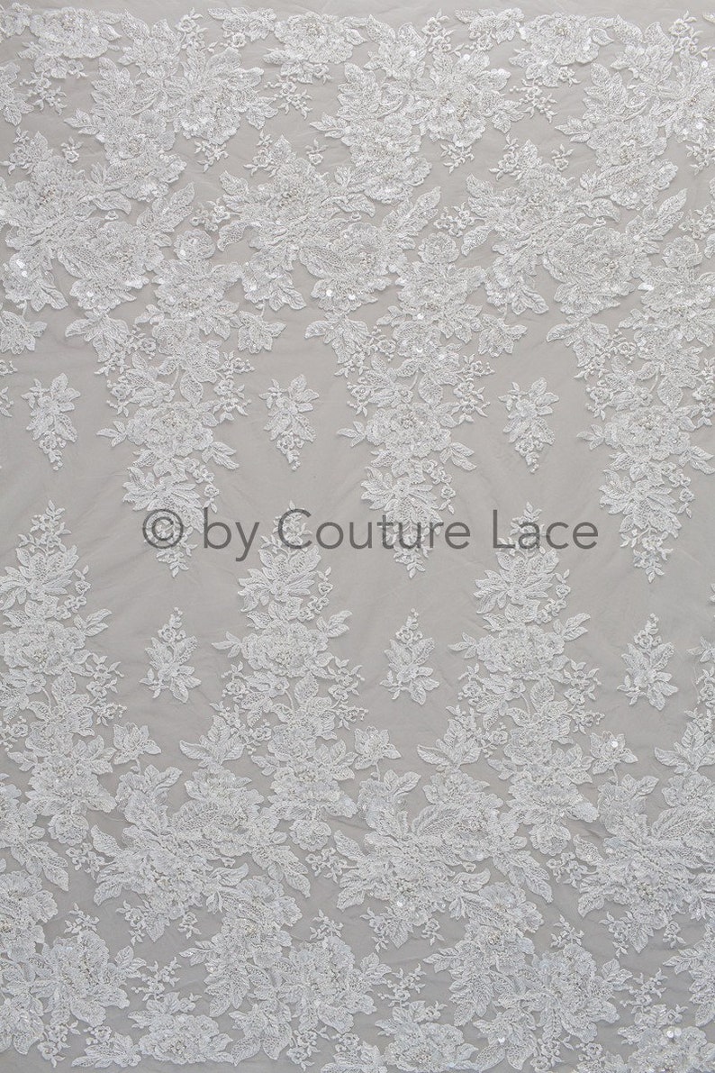 May include: White floral lace fabric with a delicate pattern and small sequins. The fabric is sheer and has a soft, flowing texture. &copy; by Couture Lace