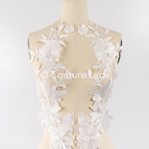 Pode incluir: Aplique de renda floral branca com um design delicado. A renda é perfeita para adicionar um toque de elegância a qualquer peça de roupa.